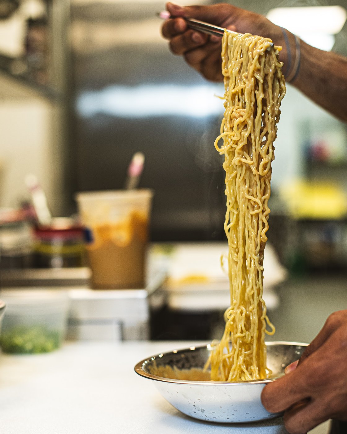 Sesame noodle pull over a steel bowl